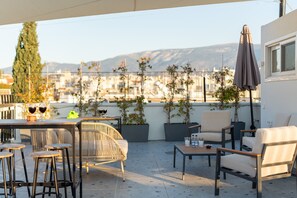A rooftop terrace with a table, chairs, and potted plants. - 2BR Gem | Near Acropolis & Metro | Rooftop Views (Athens)