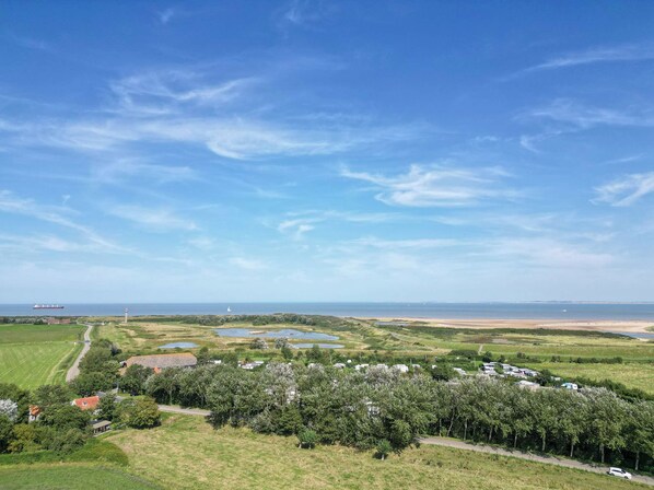 A coastal landscape with a clear sky, a lighthouse, and a marina with boats.