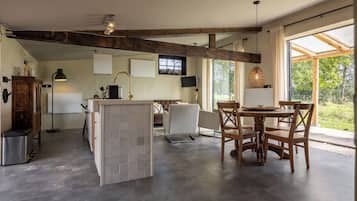 A spacious kitchen with a dining area, wooden beams, and large windows.