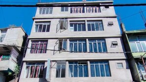 A multi-story building with a sign for 'The Lushai Inn' indicating room bookings. - THE LUSHAI INN (Aizawl)