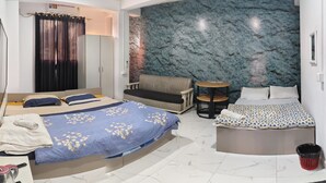 A bedroom with two beds, a sofa, a small table, and a trash bin. - THE LUSHAI INN (Aizawl)