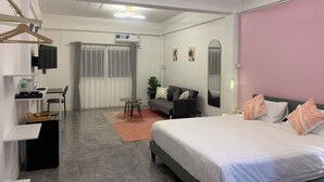 A modern bedroom with a bed, a desk, a chair, a sofa, and a TV. - Mana restaurant and boutique hotel (Khon Kaen)