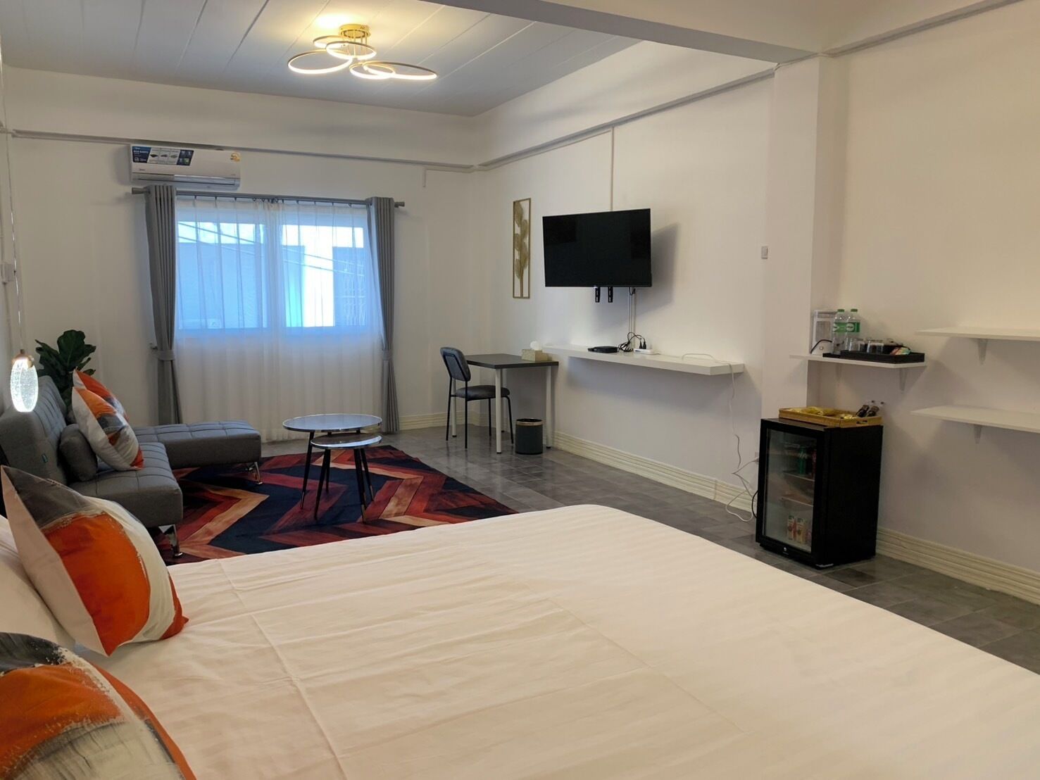 Une chambre d’hôtel moderne équipée d’un grand lit, d’un bureau, d’une chaise, d’une télévision et d’un mini-bar.