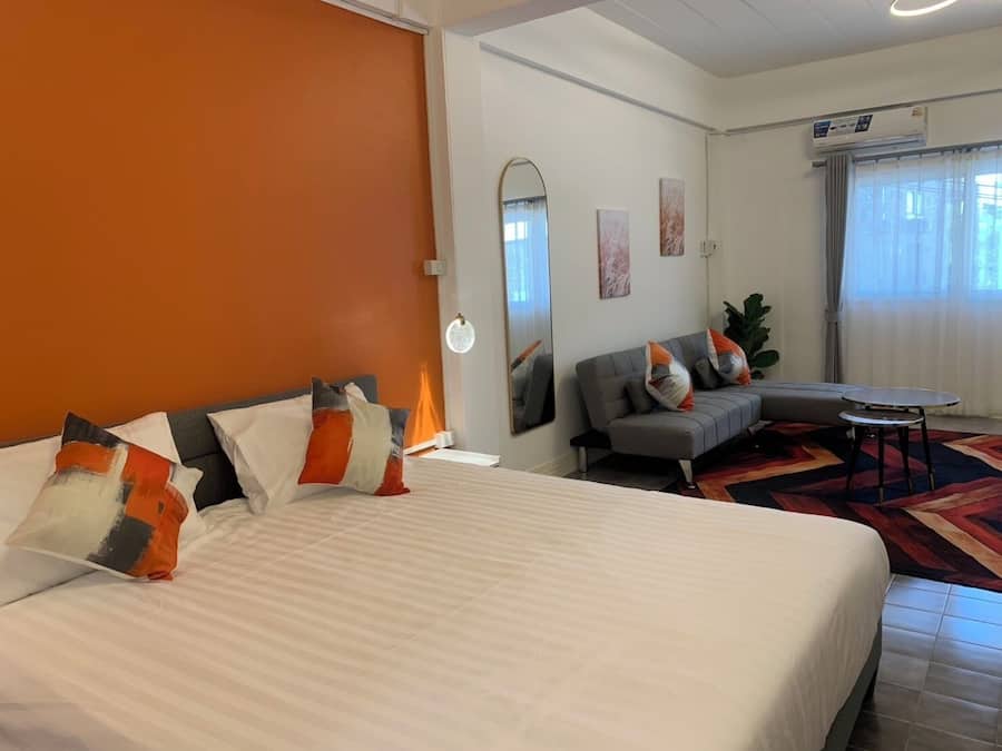 Ein Hotelzimmer mit einem großen Bett, einer Couch, einem kleinen Tisch und einem Spiegel.