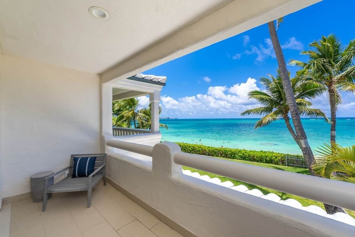 A balcony with a view of the ocean and palm trees.