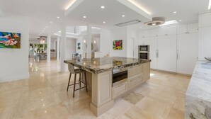 Une cuisine spacieuse dotée d’un grand îlot central, de meubles blancs et d’un éclairage moderne.