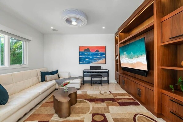A modern living room with a sofa, a coffee table, a TV, and a painting on the wall.