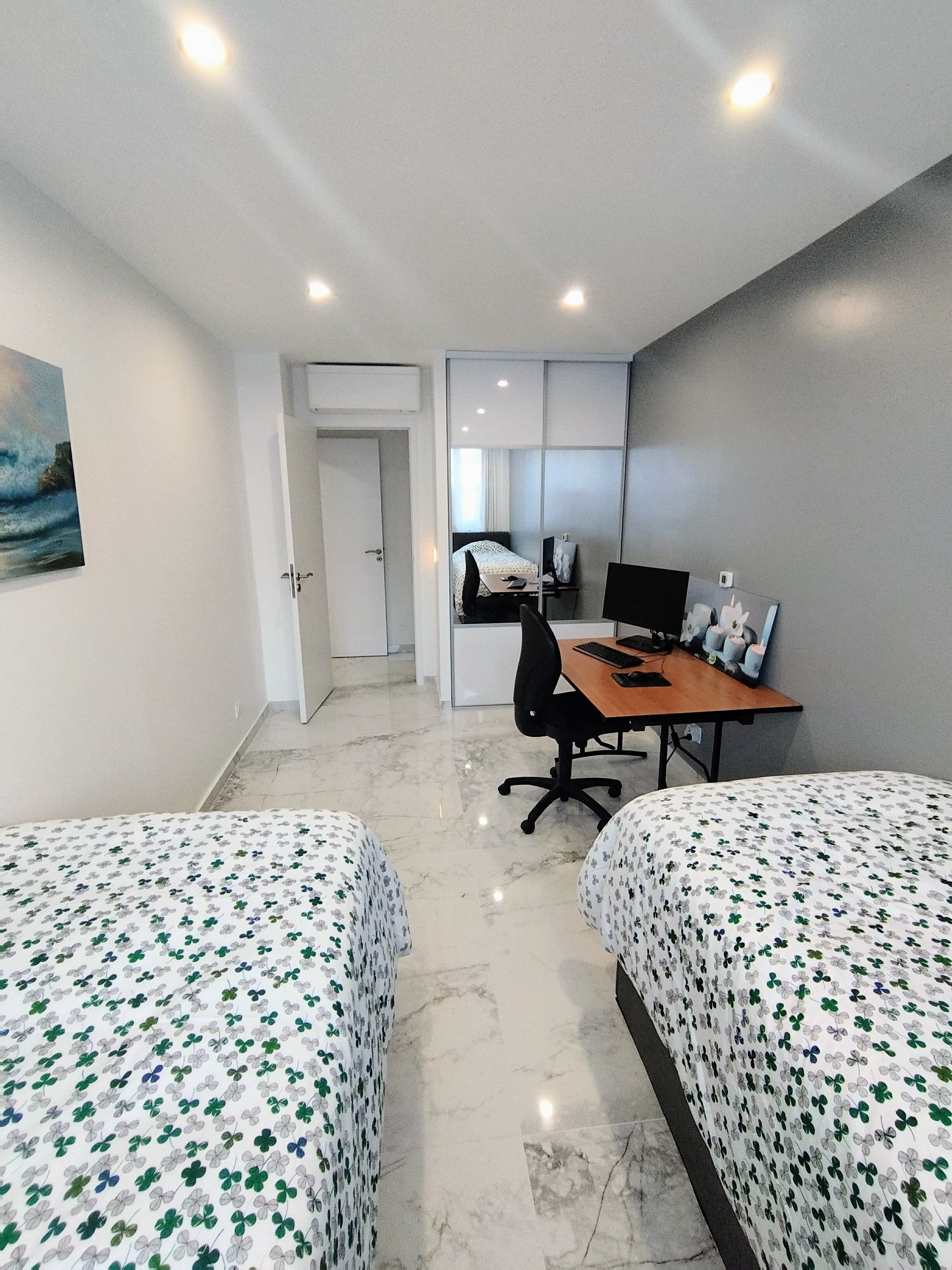 Una habitació d'hotel amb dos llits, un escriptori amb un ordinador i una petita zona de seients.