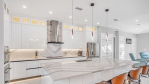 A modern kitchen with white cabinetry, a marble island, and stainless steel appliances.