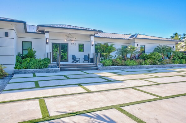 A modern building with a covered entrance, numbered 950, and a paved driveway with geometric patterns. - Paradise Oceanside Estate- 6 Bedrooms & 9 BR + Office + Theater Room – SLEEPS 14 (Marathon)
