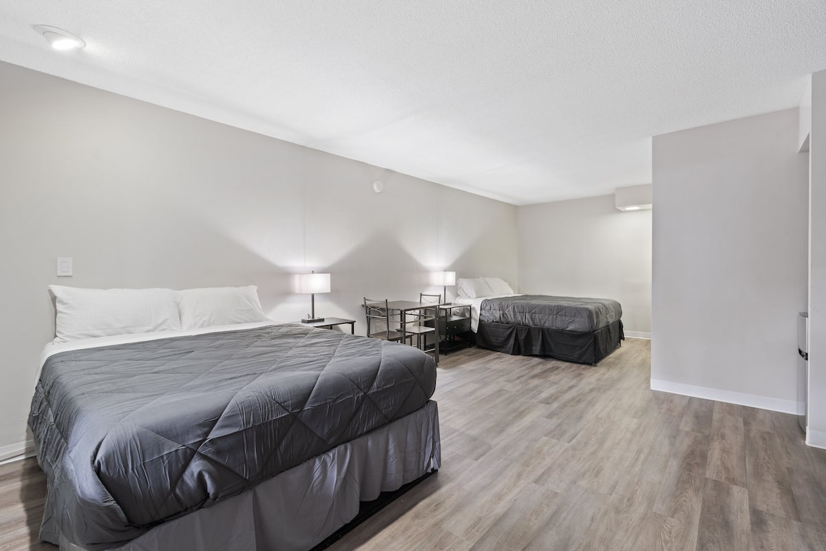 A hotel room with two beds, a desk, and a chair.