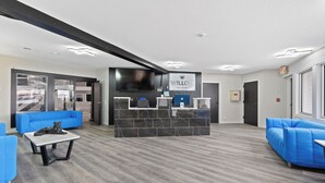 A reception area with a modern design, featuring a reception desk, blue sofas, and a marble-tiled wall. - Willow Inn Suites (Eau Claire)