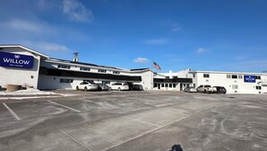 A large parking lot with a building labeled "WILLOW INN SUITES" and an American flag. - Willow Inn Suites (Eau Claire)