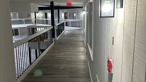 A corridor with a wooden floor, white walls, and a railing. - Willow Inn Suites (Eau Claire)