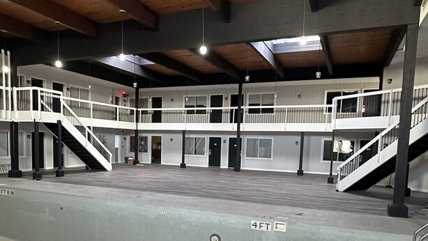 A spacious indoor area with multiple levels, including a mezzanine, and a central open space with a concrete floor. - Willow Inn Suites (Eau Claire)