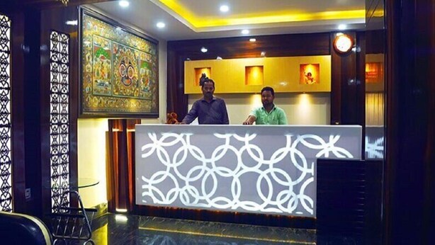 A reception area with a patterned counter, a clock, and a decorative wall. - Hotel Orion  (Bhadrak)