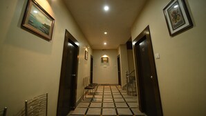 A hallway with a tiled floor, framed pictures on the walls, and a staircase at the end. - Hotel Orion  (Bhadrak)