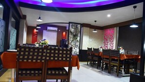 A restaurant with a modern interior, featuring a curved seating arrangement and decorative wall panels. - Hotel Orion  (Bhadrak)