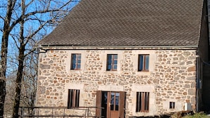 Ein Gebäude aus Stein mit geneigtem Dach und mehreren Fenstern.