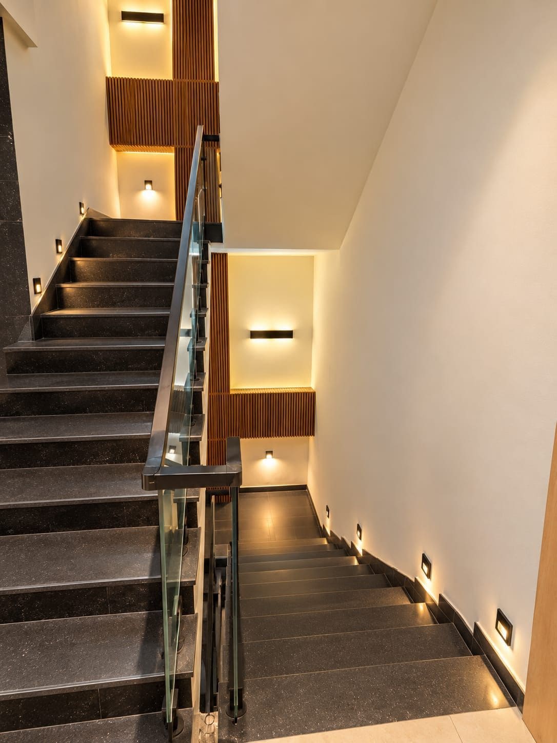 Una escalera moderna con barandillas de vidrio e iluminación integrada.