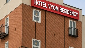 Un bâtiment d’hôtel à la façade rouge et beige, doté de nombreuses fenêtres et de climatiseurs.