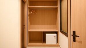 Un dressing avec des étagères en bois, une tringle à vêtements et un petit réfrigérateur.