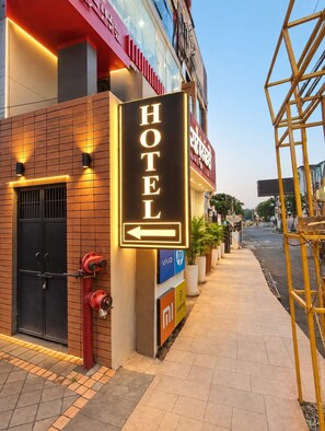 Une enseigne d’hôtel avec une flèche pointant vers la gauche, indiquant la direction de l’entrée de l’hôtel.