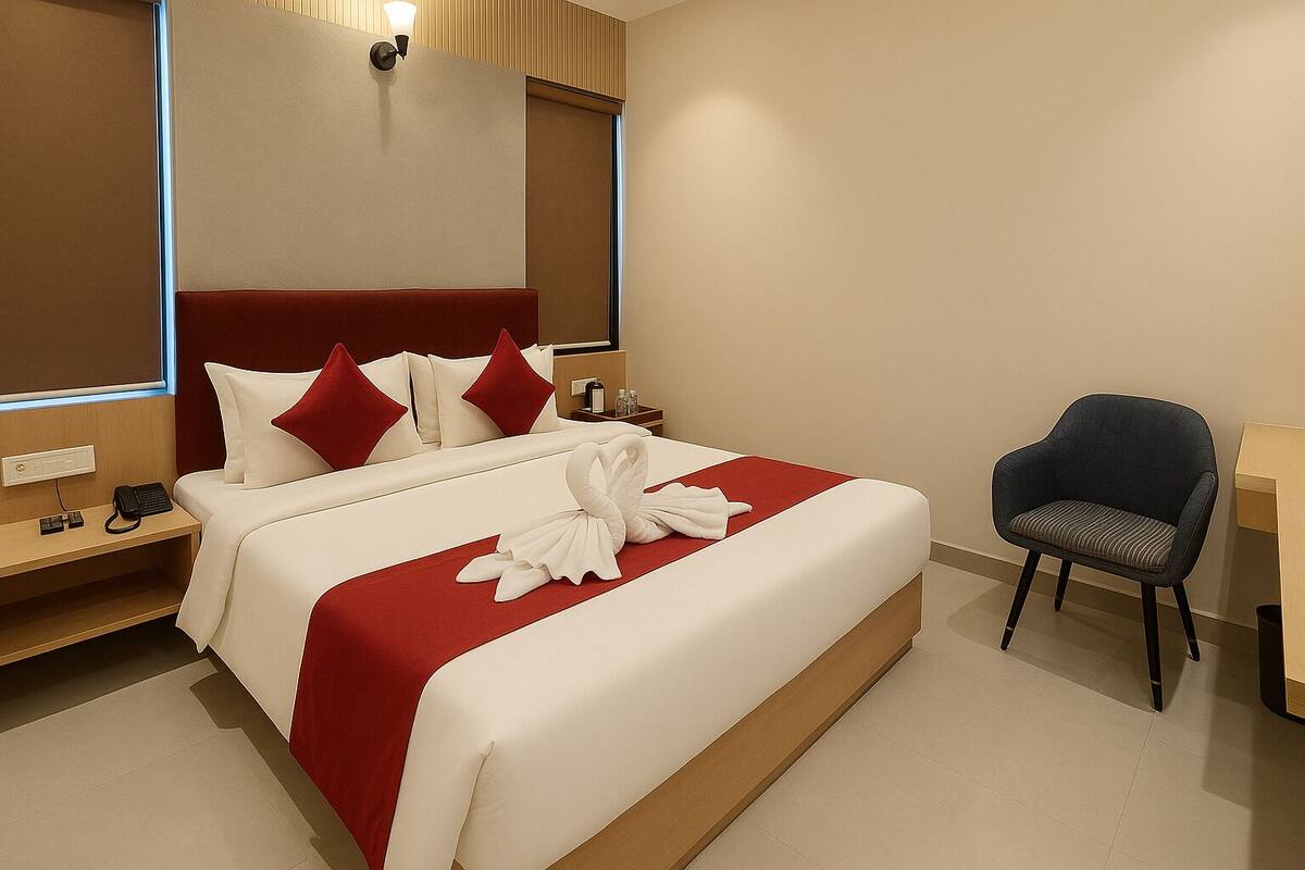 Una habitación de hotel con cama, una silla, un escritorio y un espejo.