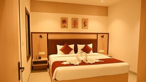 Una habitación de hotel moderna con una cama grande, un cabecero de madera y una mesita de noche pequeña.