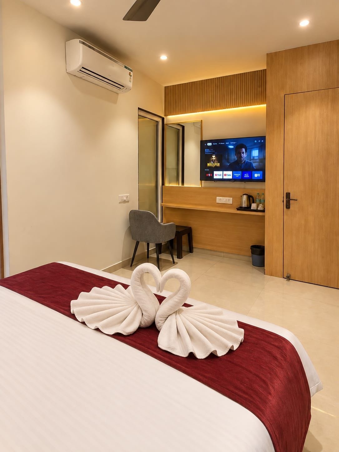 A hotel room with a bed, a desk, a television, and a mirror.