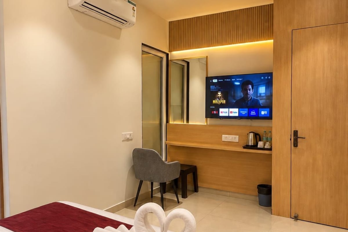 Una habitación de hotel con cama, escritorio, televisor y espejo.