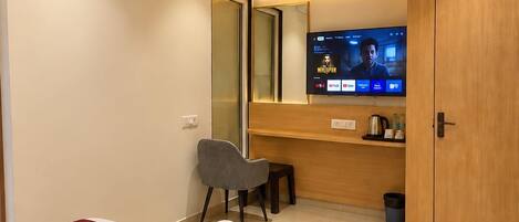 A hotel room with a bed, a desk, a television, and a mirror.