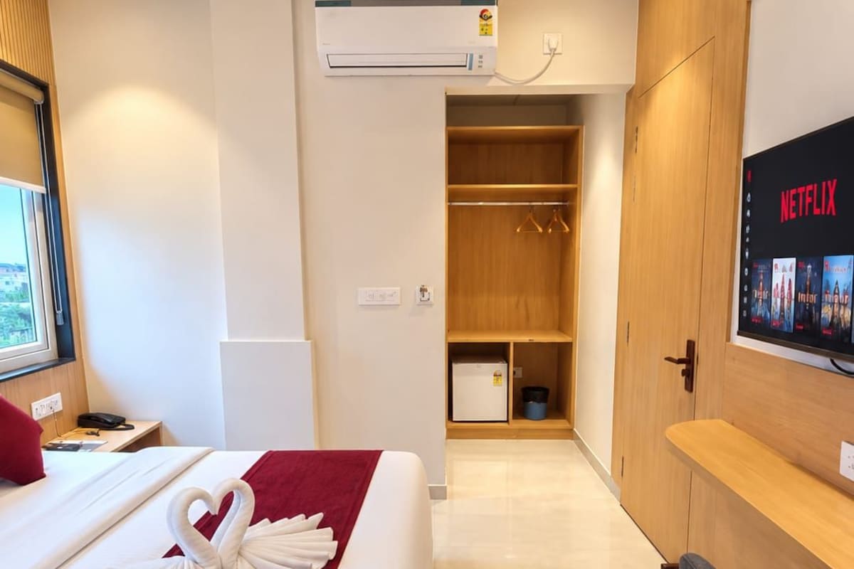 Una habitación de hotel con cama, televisor mostrando Netflix, armario y baño.