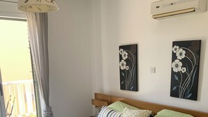 Ein Schlafzimmer mit einem Bett, Kissen, einer Pendelleuchte und zwei Wandklimaanlagen.