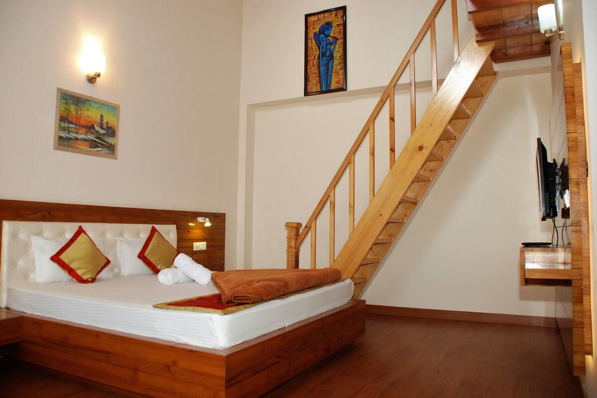 Une chambre avec un lit en bois, un escalier en bois et un tableau accroché au mur.