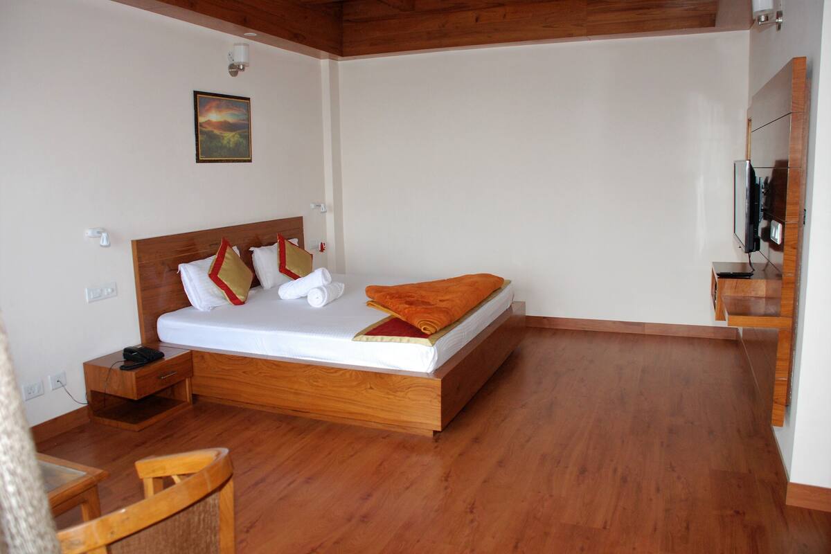 Une chambre à coucher avec un lit en bois, une table de chevet, une chaise et un tableau accroché au mur.