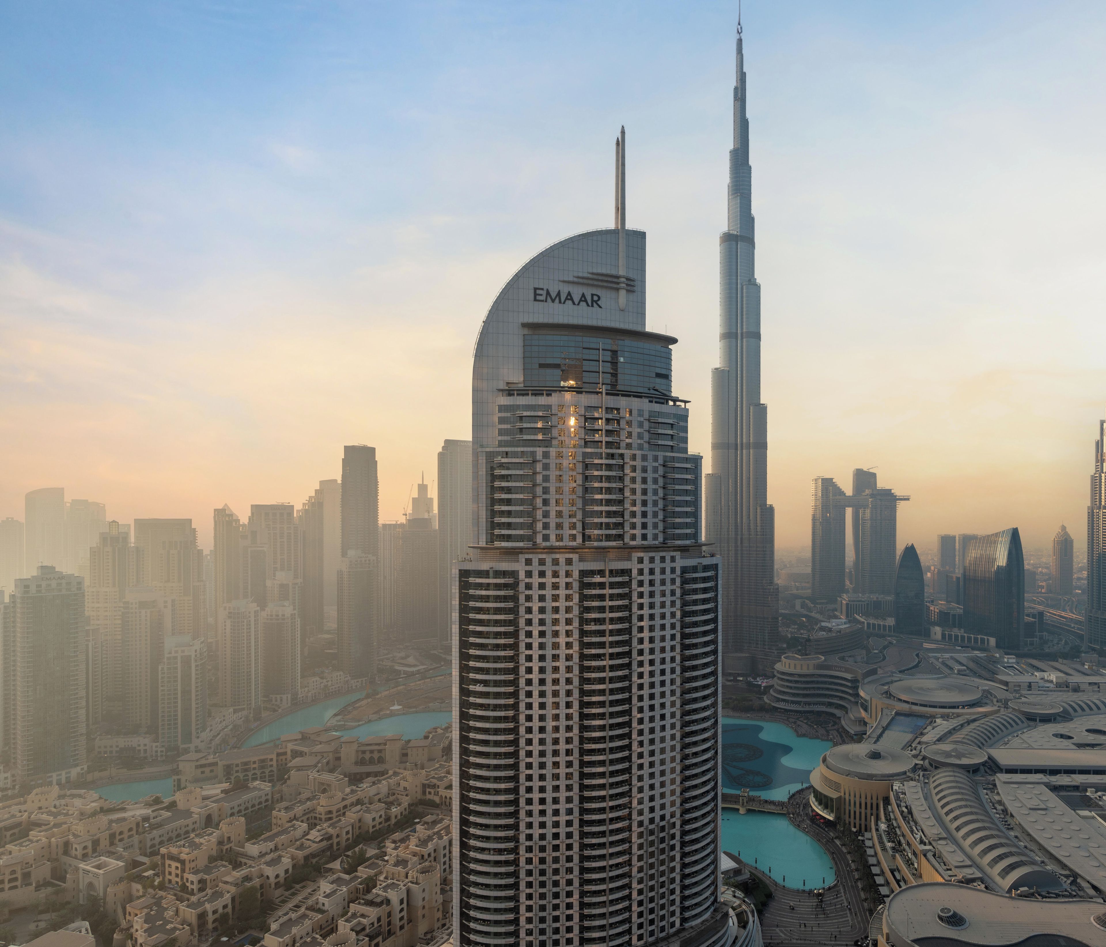A high-rise building with a curved top and a prominent vertical tower in the background.