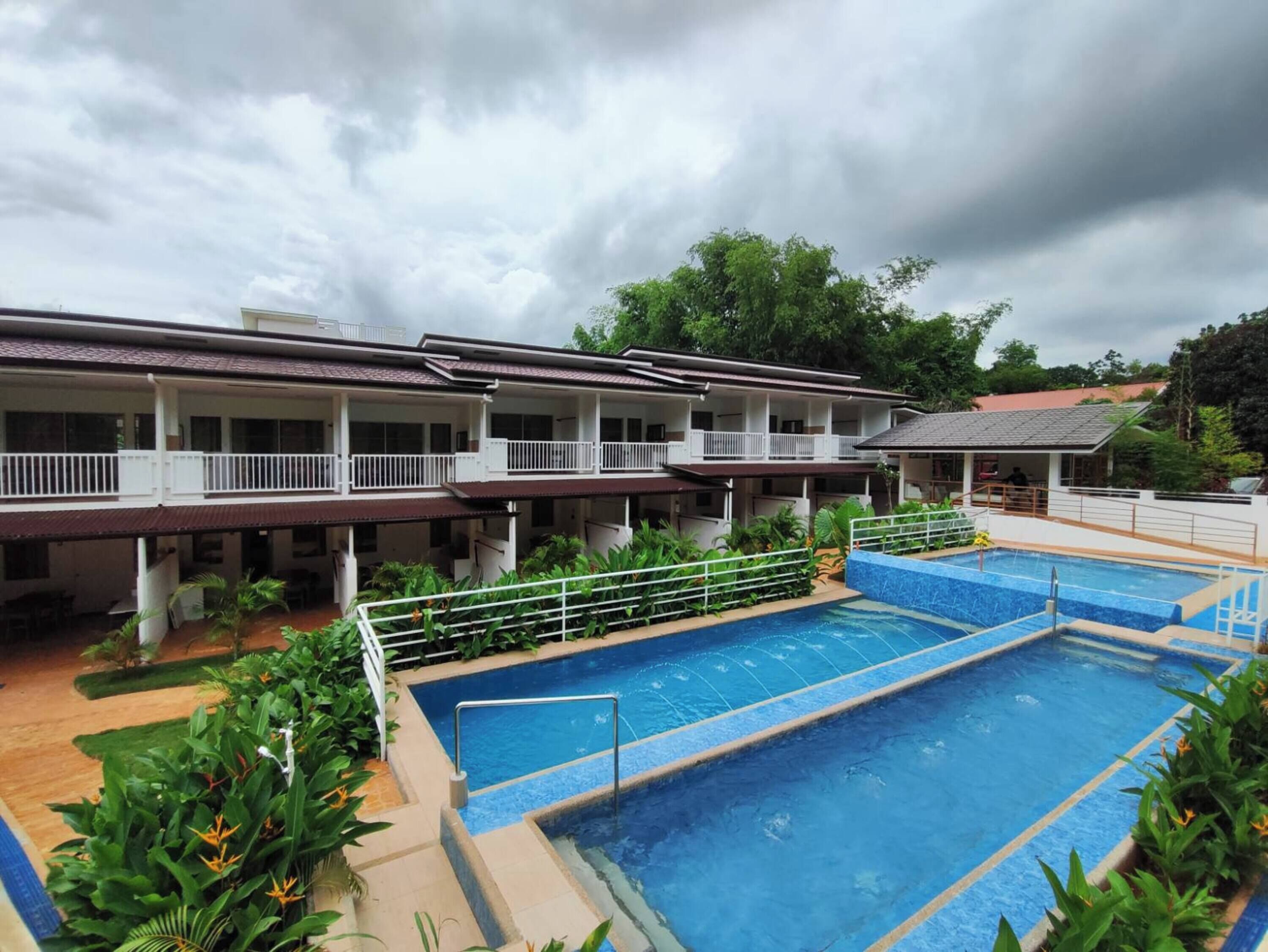 A hotel with a swimming pool, multiple balconies, and lush greenery.
