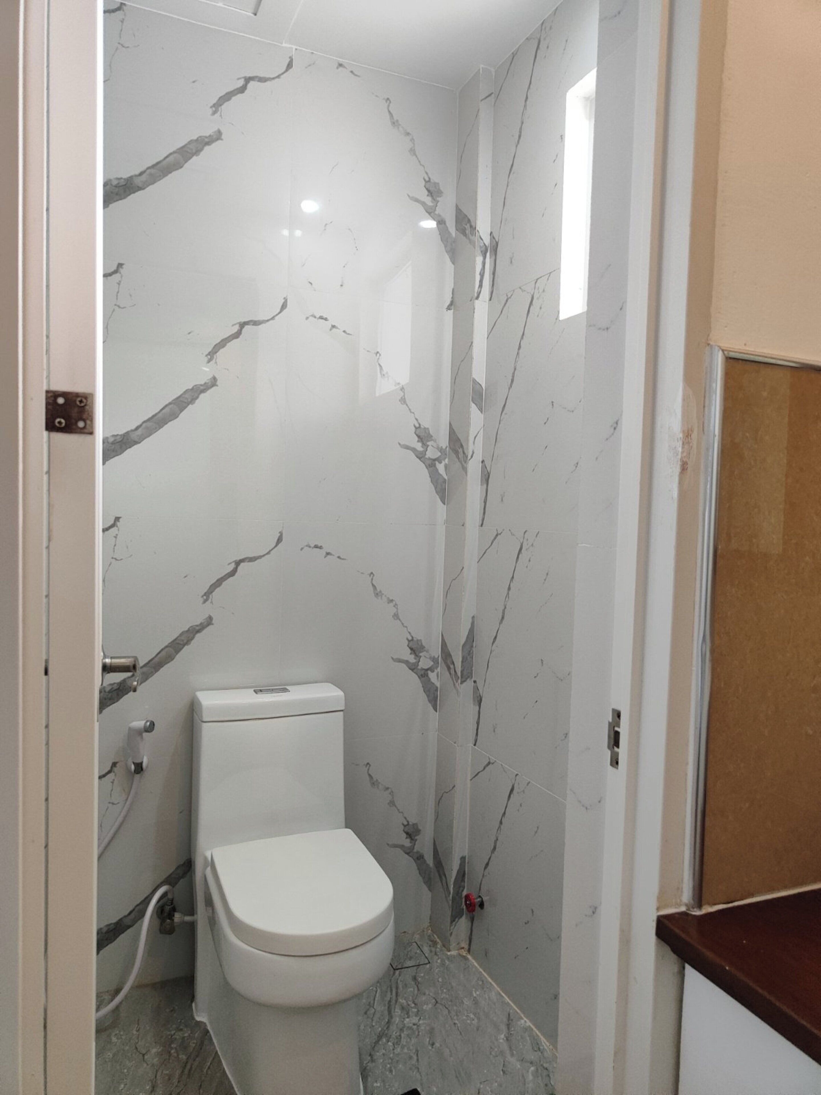 Een badkamer met toilet, marmeren wanden en een douchehoek.