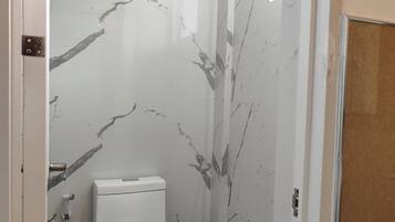 Een badkamer met toilet, marmeren wanden en een douchehoek.