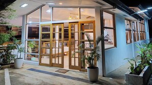 A modern building with a glass facade, a covered entrance, and potted plants. - DMC Condotel (Puerto Princesa)