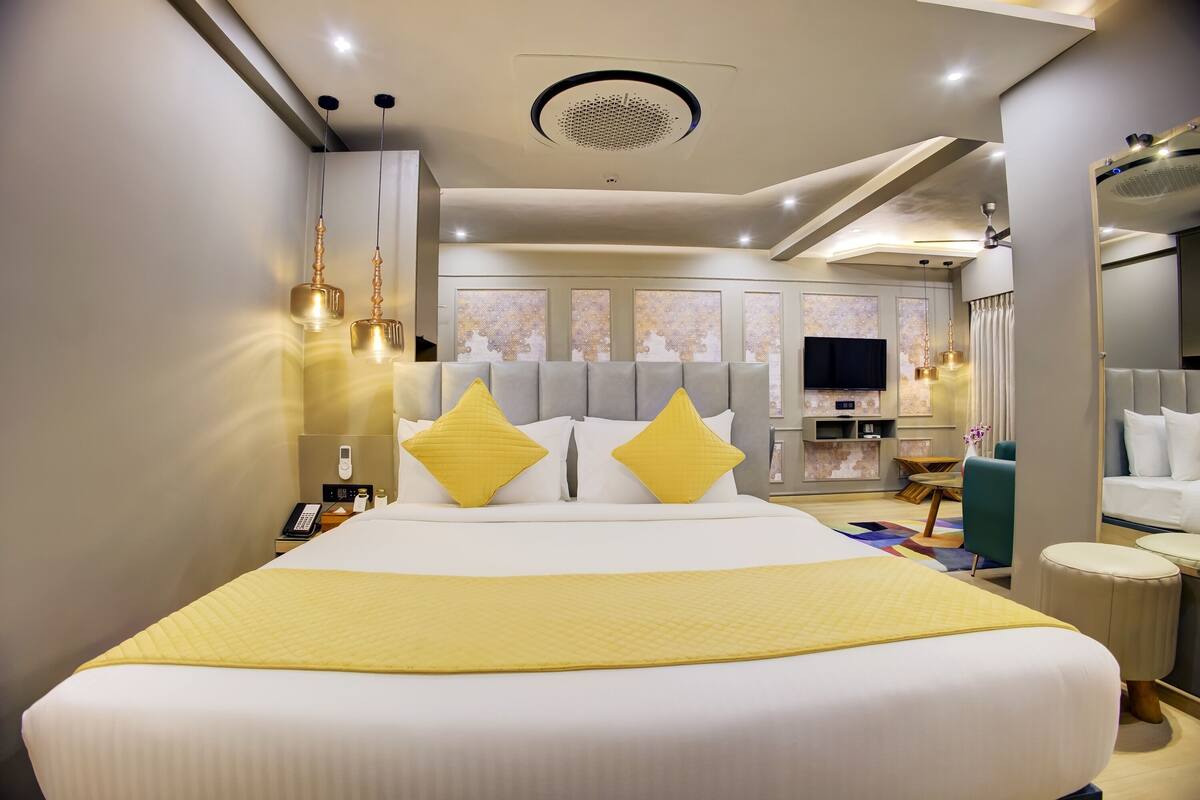 Quarto de hotel com uma cama grande, televisão, escrivaninha e espelho.