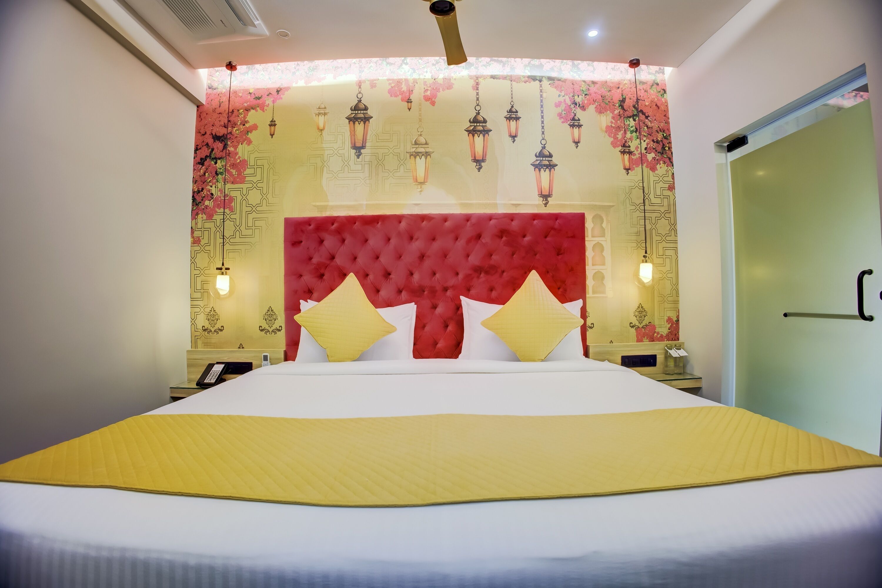 A hotel room with a large bed, a red headboard, and decorative wall panels.