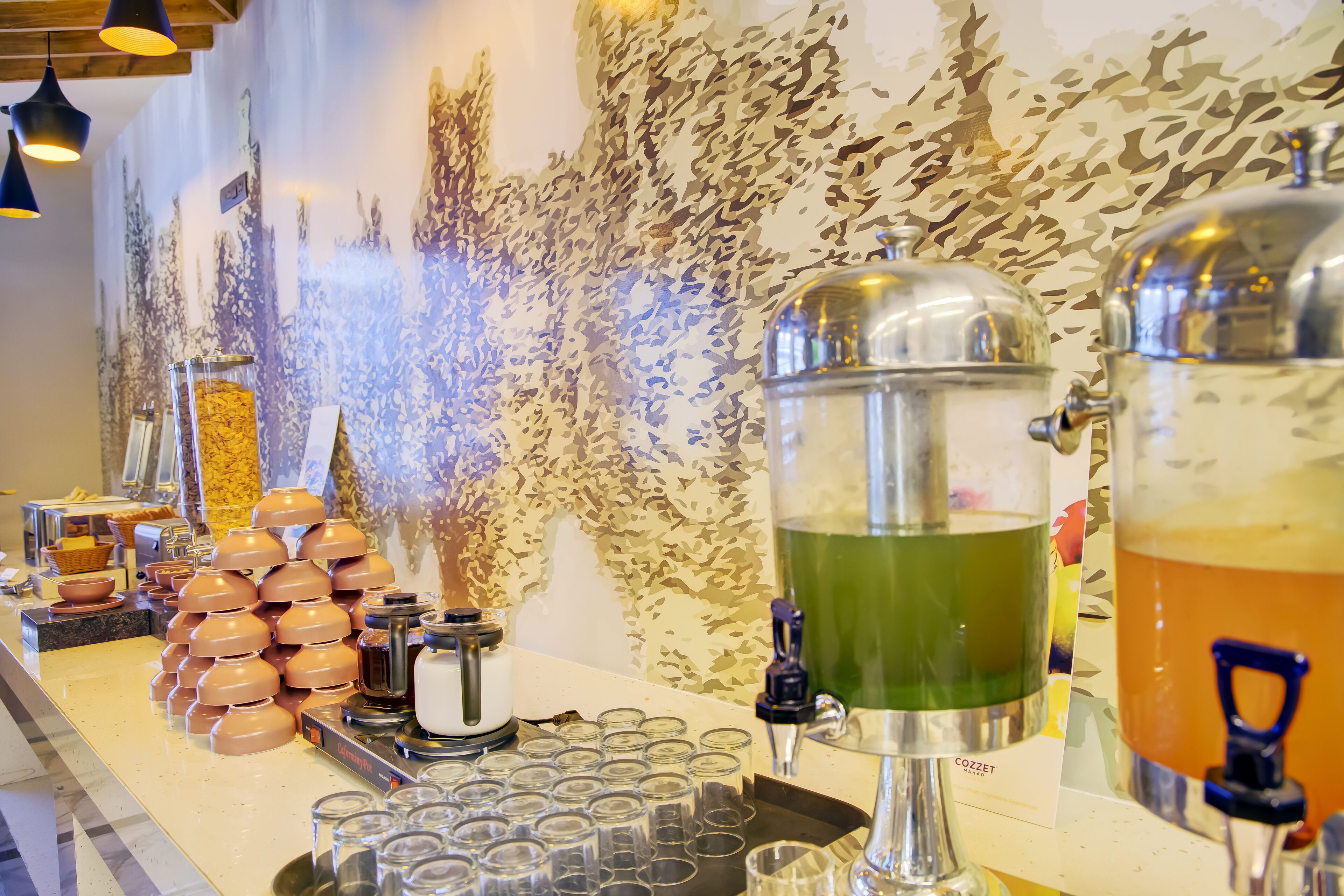 A buffet setup with various food and drink dispensers, including a coffee machine and a tea dispenser.