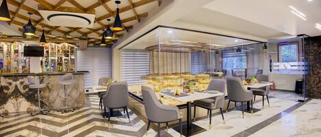 A modern hotel lobby with a bar area, seating with a glass partition, and a marble floor.
