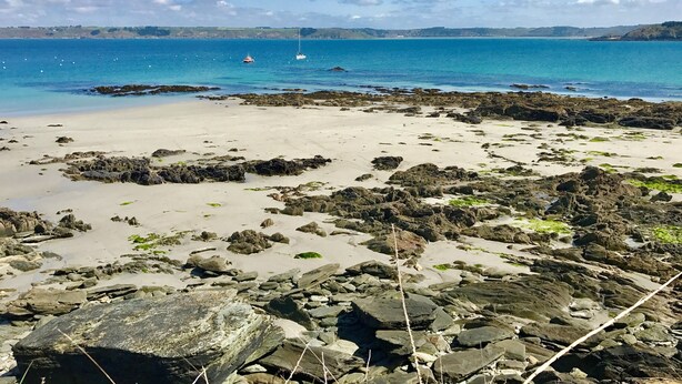 A rocky beach with clear blue water and distant boats. - 4-bedroom house for 8 people, 7 km from the beach. (Plouégat-Guérand)
