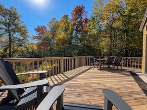 A wooden deck with outdoor seating and a view of trees.