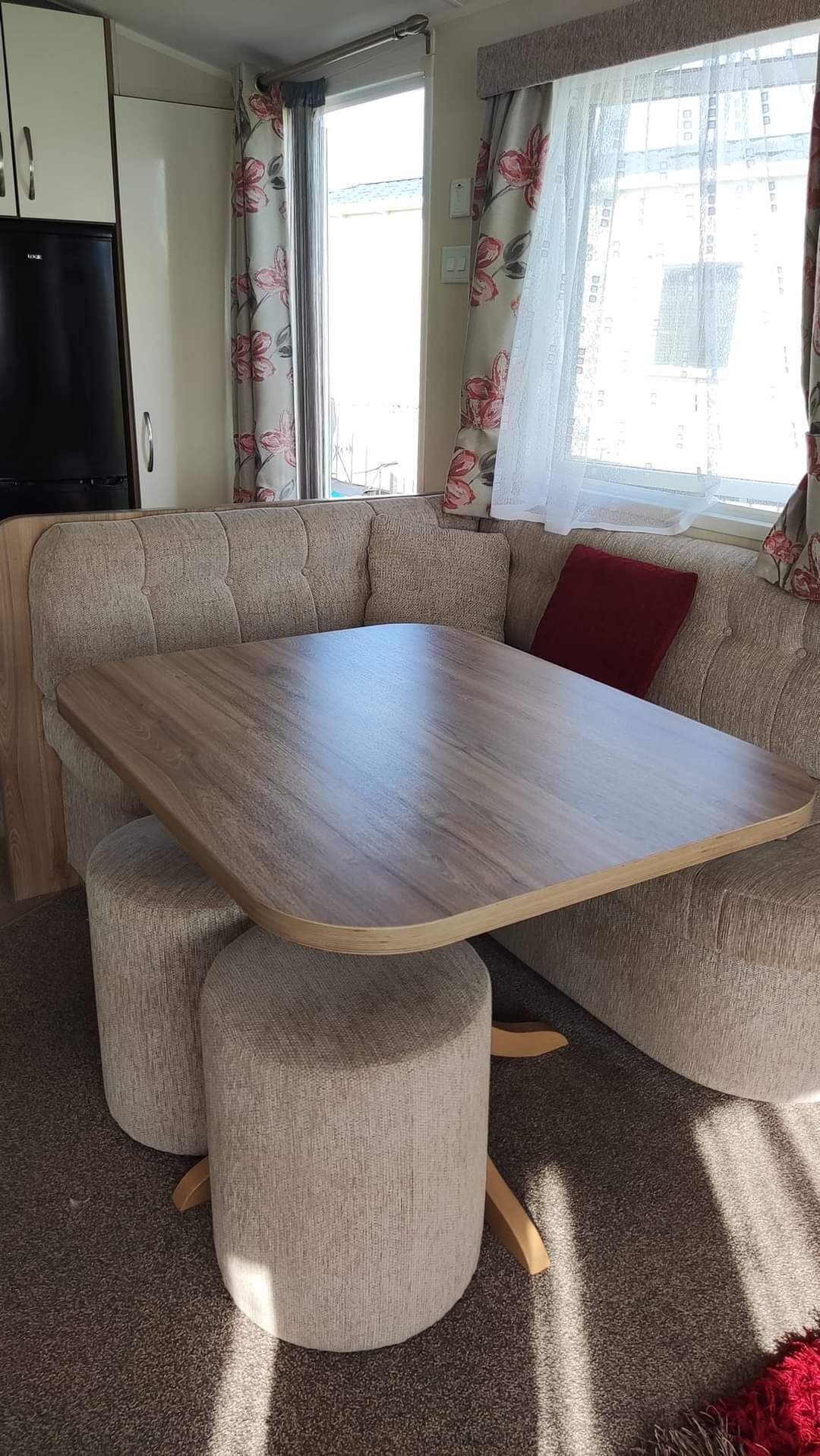 A compact living space with a sofa and a wooden table, a television, and curtains with a floral pattern.