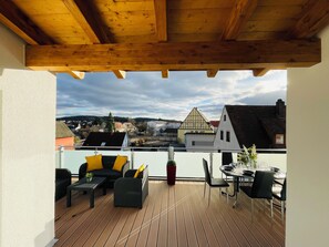 A wooden deck with outdoor furniture, a dining table, and chairs.