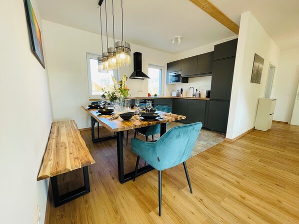 A modern kitchen with dark cabinets, a wooden dining table, and blue chairs.